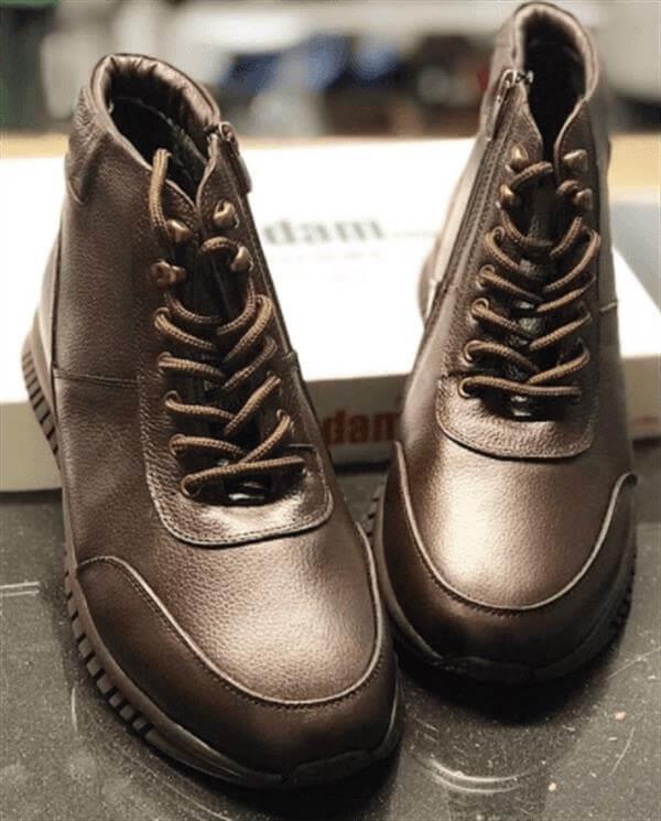 AG7044 kahve deri bot çiftinin mağaza tezgâhında önden görünümü; kahve bağcıklar, metal donanım ve arkada kutu
